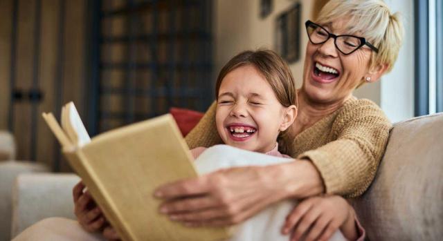 El TSJCV reconoce por primera vez el derecho a percibir el complemento por brecha de género en su pensión a una jubilada por el cuidado de su nieta, a la que tuvo durante años en acogimiento familiar. Imagen de una abuela y su nieto leyendo un libro y riendose juntos