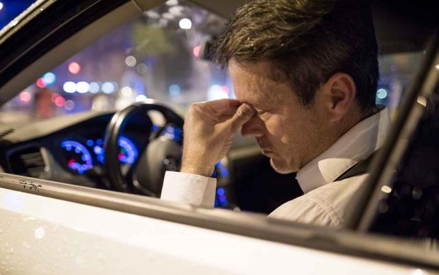 Accidente de trabajo. Imagen de hombre sentado en un coche con gesto de enfermedad