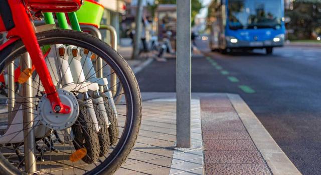 Nuevas obligaciones sociolaborales para empresas y sector público Planes de movilidad sostenible al trabajo en la Ley 9/2025. Imagen de unas bicicletas y scooters estacionadas en una acera