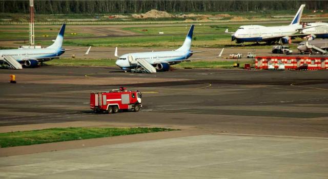 Bomberos de AENA. Camión de bomberos en pista de aeropuerto cerca de varios aviones