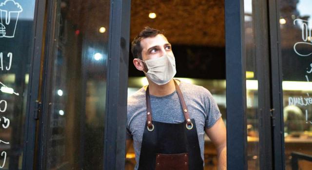 Ayudas para hostelería y autónomos. Empleado con mascarilla cerrando la puerta de una cafetería