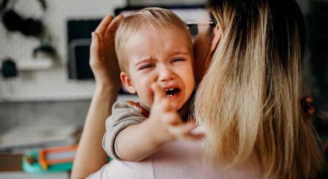 Prestación por nacimiento y cuidado de menor; familias monoparentales. Bebé llorando en brazos de su madre que trata de calmarlo