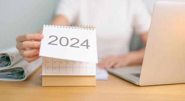 Fiestas laborales 2024. Imagen de una mujer en un escritorio mirando el calendario de 2024