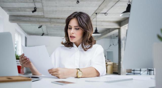 La valoración de si la causa está suficientemente descrita debe tomar en cuenta el contexto en que se adopta el despido. Mujer de negocios sentada en una mesa de trabajo y preocupada ante carta de despido frente a ordenador