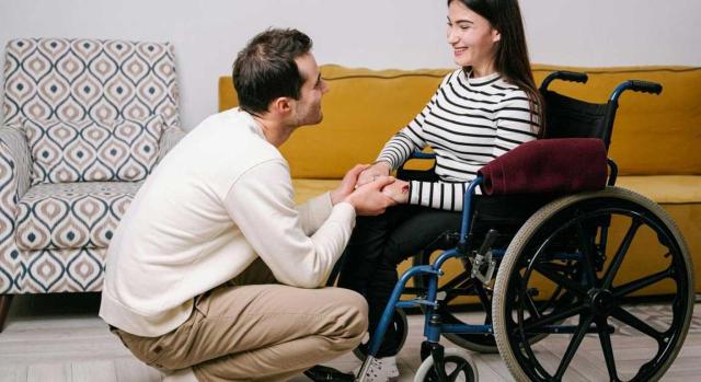 Prestación familiar por hijo mayor a cargo con un grado de discapacidad igual o superior al 65 por ciento Prestación en favor de familiares por hijo discapacitado a cargo. Fecha de efectos económicos. Supuesto en el que la prestación ya está reconocida durante la minoría de edad del hijo y se deja sin efecto al alcanzar la mayoría de edad. Imagen de una chica en silla de ruedas hablando con un hombre