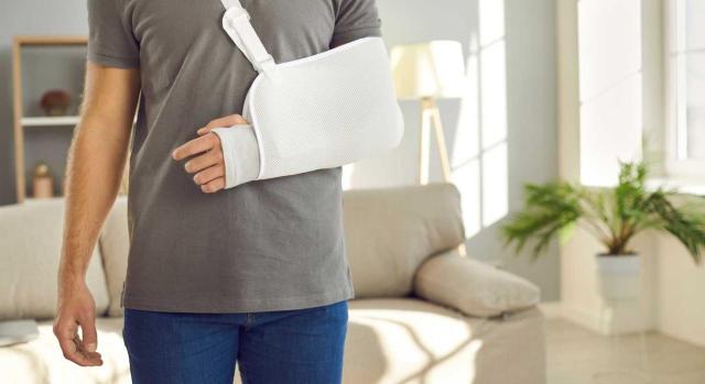 Cabe el reintegro de gastos médicos cuando el tratamiento incierto e improductivo de la mutua lleva a pedir atención médica privada que genera un buen resultado. Imagen de un chico con el brazo en cabestrillo en el salón de su casa