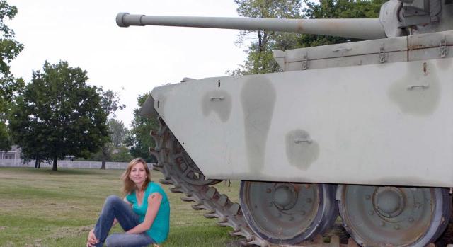 Mujer sentada al lado de un tanque militar