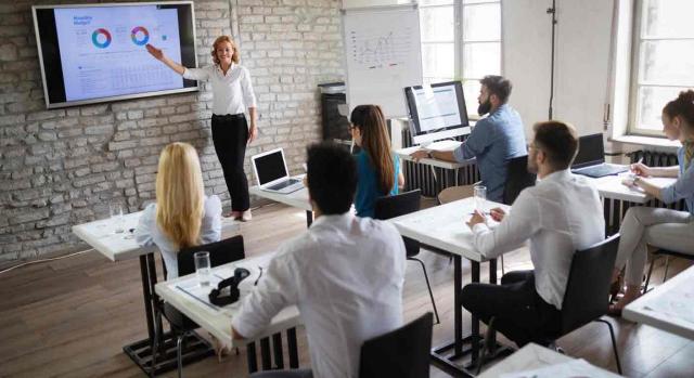 Alumnos adultos atienden atentamente a su profesora en un curso de formación