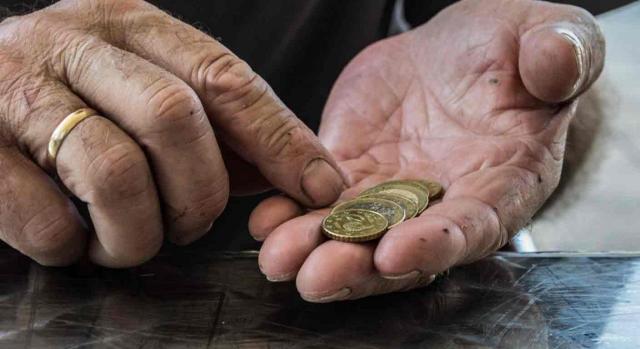 Complemento por mínimos; efectos económicos; retroactividad. Las manos de un hombre mayor con unas monedas en la mano