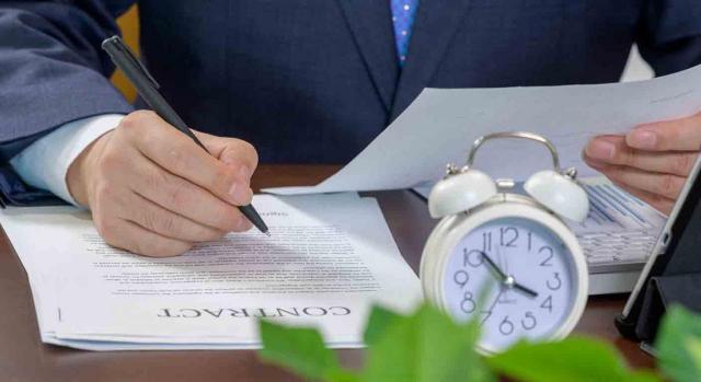 Empresario revisando un contrato y reloj sobre la mesa