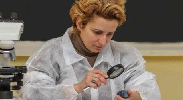 Nueva modalidad de contrato indefinido para actividades científico-técnicas. Imagen de mujer investigadora observando minerales con lupa