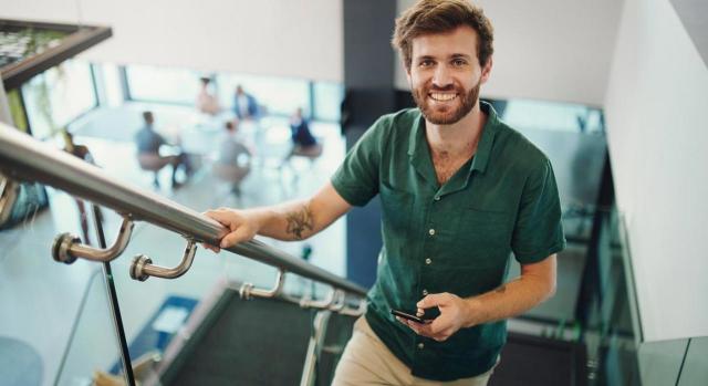 Cambios en la regulación del convenio especial con la Seguridad Social de los becarios. Imagen de hombre sonriente subiendo escaleras