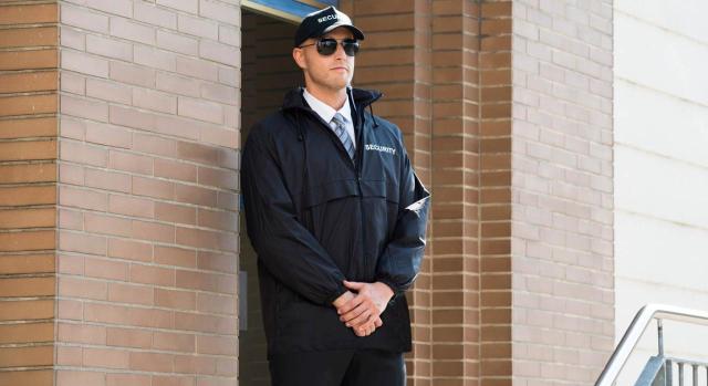 Únicamente procede abonar el plus de transporte. Guardia de seguridad masculino de pie en una entrada