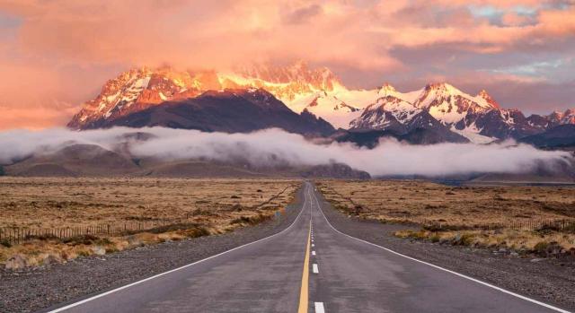 Convenios Colectivos. Vista de una carretera vacía con montañas de fondo y cielo anaranjado