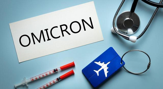 Continúan hasta el 29 de diciembre las medidas excepcionales para hacer frente a la variante ómicron. Imagen con un cartel con la palabra omicron acompñada por una tarjeta con un avión