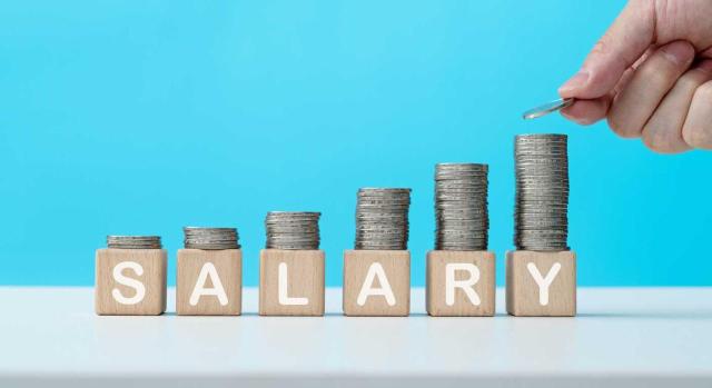 RD 126/2026 y art. 28 del RDL 5/2026 En 2026 sube el SMI y sigue sin tributar en el IRPF. Imagen de unas monedas sobre unos cubos con la palabra salario en forma de gráfica creciente