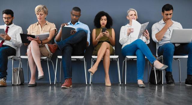 Aprobado el Real Decreto-ley que simplifica y mejora el nivel asistencial de la protección por desempleo. Imagen de seis personas esperando en una silla para una entrevista de trabajo