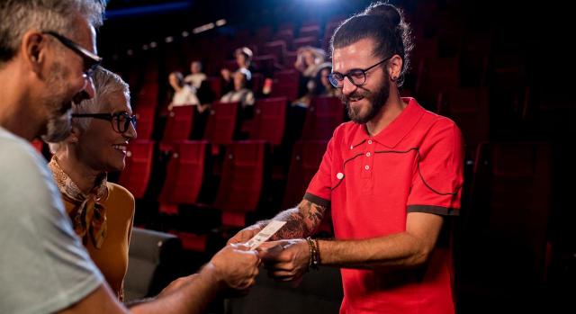 Indemnización por despido improcedente tras sucesión de contratas. Imagen de una pareja en un teatro entregando el ticket de sus asientos a un chico