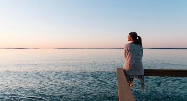 No se ha aportado una justificación objetiva y razonable de la medida adoptada. Imagen de mujer joven sentada en el borde de una estructura de madera mirando el mar