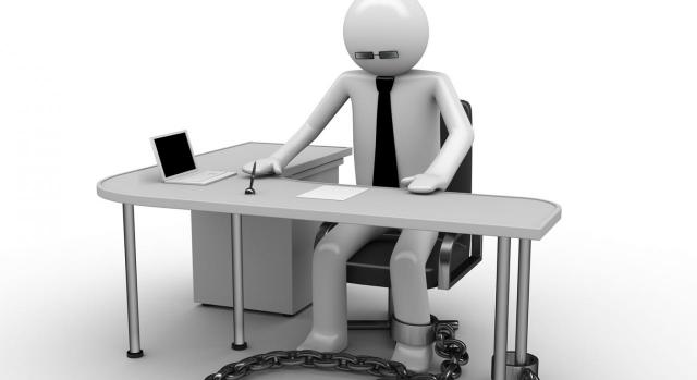 Prioridad de permanencia. Imagen de trabajador, representado en un muñeco, encadenado a la mesa de trabajo