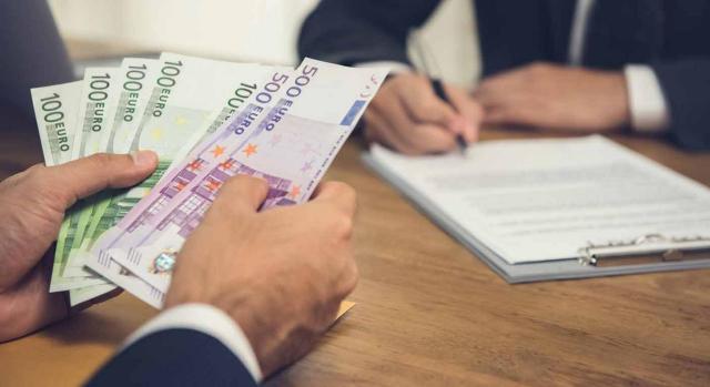 Empresario tramitando un acuerdo Empresario contando billetes de euro mientras tramitan un acuerdo