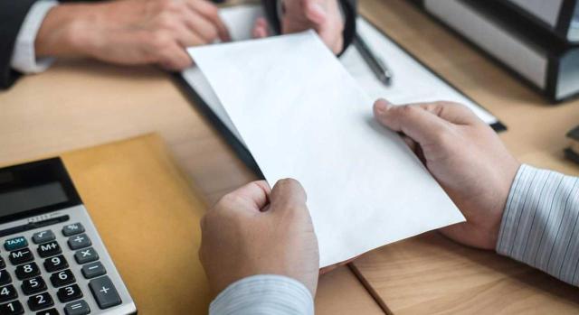 Licencias retribuidas: la empresa no puede exigir que se justifique día a día la continuidad del permiso de 5 días por hospitalización de familiares. Imagen de la entrega de un documento en un escritorio de trabajo