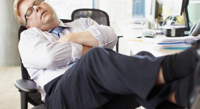 Falta de ocupación efectiva. Imagen de un empresario durmiendo en su escritorio
