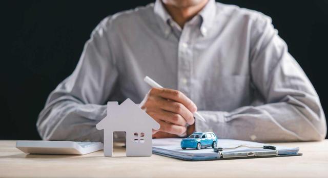 Vivienda, vehículo y préstamos: cómo valorar correctamente estas retribuciones en especie en la nómina. Imagen de un hombre sentado preparando para firmar el contrato de vivienda y de coche