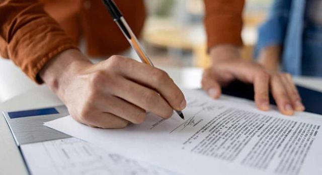 Cláusulas contractuales laborales: cómo proteger a la empresa sin vulnerar los derechos del trabajador. Imagen de un hombre firmando un documento