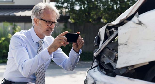 La falta de cotización se proyectó sobre la cuantía de la base reguladora. Imagen de hombre fotografiando el siniestro de un automovil