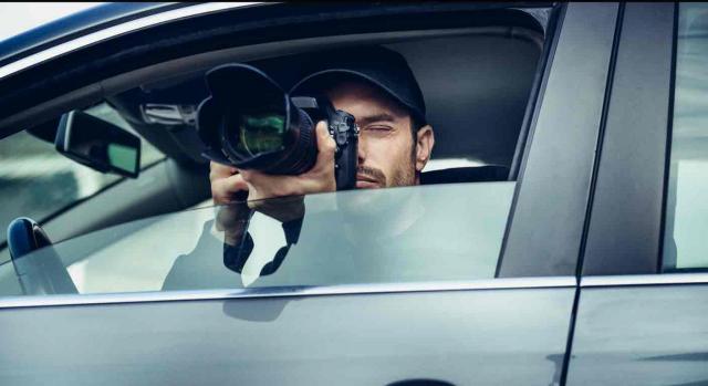 Gastos de detective. Detective tomando una foto desde el interior de un coche