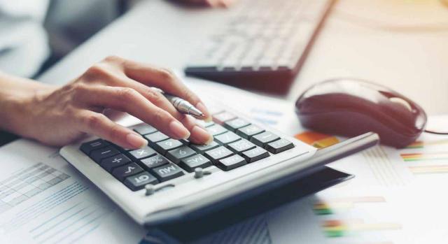 Gran invalidez. Mujer frente a un teclado, haciendo cálculos con una calculadora