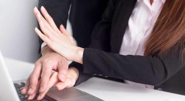 Despido disciplinario por acoso sexual: la importancia de que la comunicación escrita contenga una descripción clara, concreta y precisa de los hechos, días e identidades. Imagen de un hombre acosando a una mujer mientras trabajaba tocándola la mano