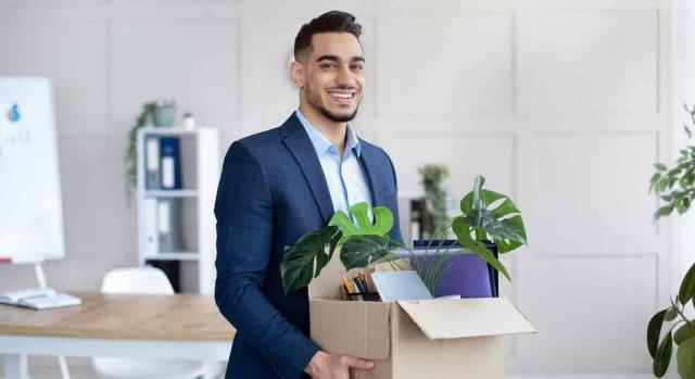 Cómo frenar el abandono del puesto por los trabajadores. Un hombre joven lleva una caja con sus pertenencias para instalarse en su nueva oficina