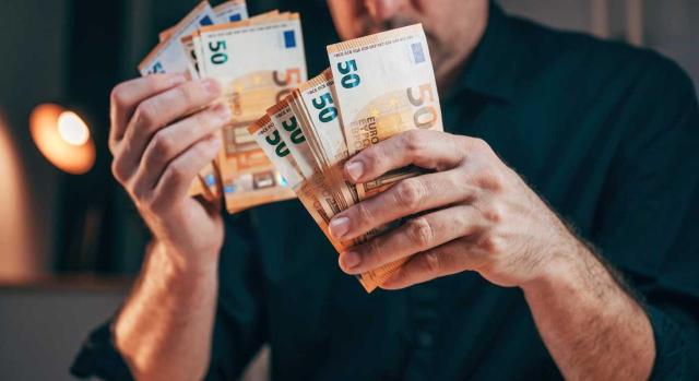 Subsidio por desempleo. Límite de rentas. Pacto en el que se fija una indemnización por despido colectivo superior a la legal El Tribunal Supremo recuerda que el importe que exceda de la indemnización legal por despido colectivo ajustado a derecho computa como renta a efectos de determinar el límite legal para lucrar el subsidio por desempleo. Imagen de un hombre con varios billetes de 50 euros entres sus manos