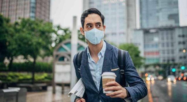 Trabajador con mascarilla y con un café en la mano