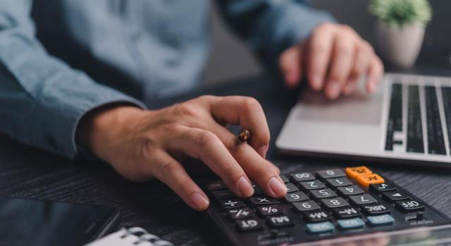 Indemnización a tanto alzado por fallecimiento derivado de enfermedad profesional: debe calcularse de acuerdo con la base reguladora utilizada para el cálculo de las prestaciones, sin el límite de la cuantía máxima de las pensiones. Imagen de un hombre con calculadora y portátil