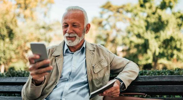 jubilación anticipada; trabajadores fijos discontinuos; requisitos; periodo de inactividad. Un hombre usa su smartphone sentado en el banco de un parque