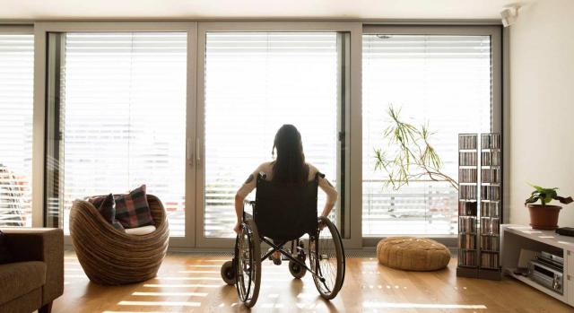 Se considera situación análoga a la orfandad absoluta. Mujer discapacitada en silla de ruedas frente a un ventanal