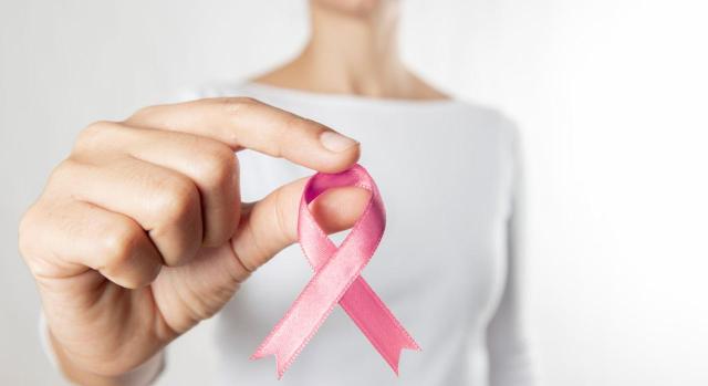 La persona que sufre un cáncer derivado de un tumor avanzado no puede considerarse hábil para desempeñar una actividad por el hecho de que exista remisión. Imagen de una mujer con el lazo rosa de prevención de cáncer de mama