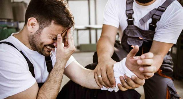 Incapacidad permanente total. Trabajador con la mano lesionada y gesto de dolor