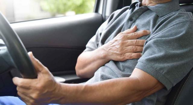 Infarto de miocardio. Imagen de un señor conduciendo con la mano en el corazón