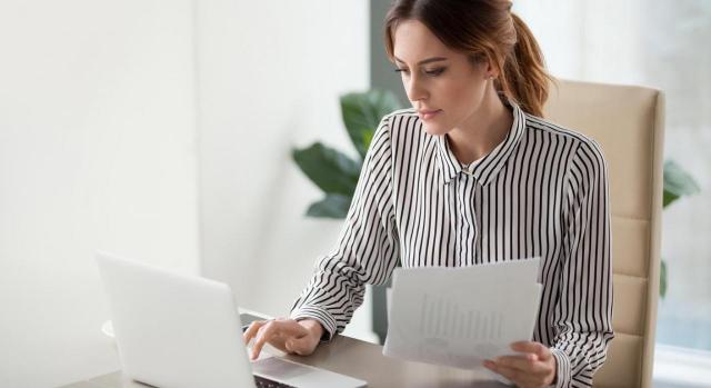 Observatorio de la OIT sobre el mundo del trabajo. Imagen de mujer frente a portátil con un documento en la mano