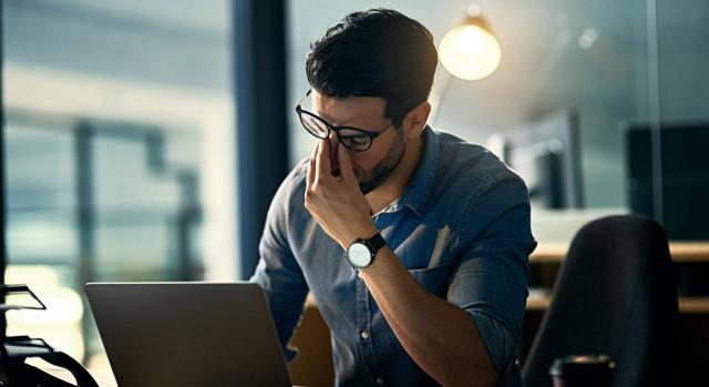 Interinidad vacante. Imagen de hombre cansado trabajando con portatil