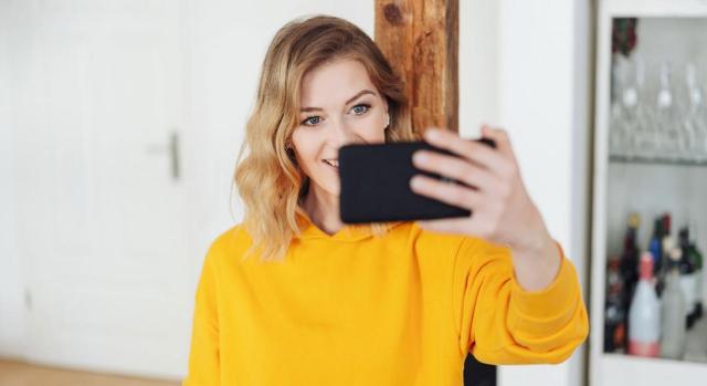 La empresa editora no puede utilizar la imagen publicada en FB. Imagen de una joven sonriente haciéndose un selfie en casa