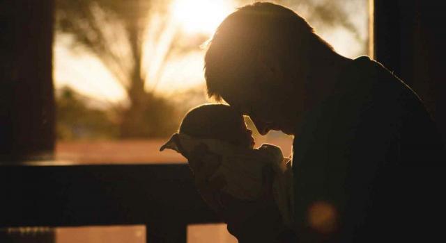 En la Mutualidad de la Abogacía la cobertura de la protección por maternidad es obligatoria. Imagen de un papa sostiendo en sus brazos a su bebé