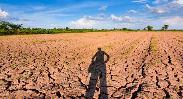 Medidas para enfrentar la crisis energética, la inflación y la sequía. Imagen de la sombra de una persona en un campo agrietado por la sequía