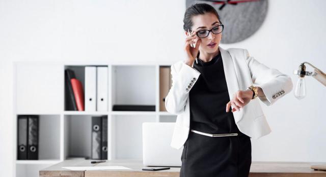 Modificación sustancial en horario de jornada. Mujer mirando reloj en la oficina