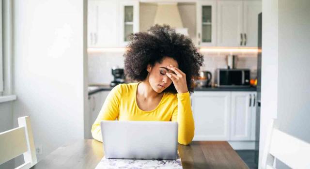 Extinción del contrato a instancia del trabajador; acoso laboral; mobbing; teletrabajo. Mujer con su portátil trabaja en la cocina de su casa con cara de cansancio