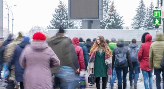 Empleo público; personal fijo; personal indefinido no fijo. Imagen nítida de una joven cruzando en un paso de peatones en dirección opuesta al resto de personas que aparecen borrosas